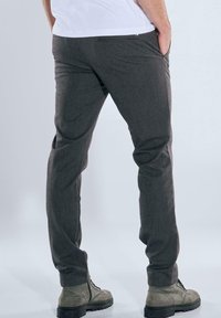 Graue Hose aus strukturiertem Stoff, mit schmaler Passform und seitlichen Taschen. Kombiniert mit grauen Stiefeln für einen vollständigen Look.