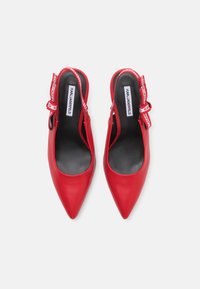 Raudoni odiniai slingback kulniukai su smailiu nosiu, juodu vidiniu pamušalu ir kaspino akcentu, kuriame yra prekės ženklo juostos detalė.