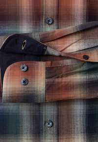 Geruit overhemdbroek met opgerolde mouwen, voorzien van zwarte knopen en een patroon van bruine, beige en donkergroene tinten.