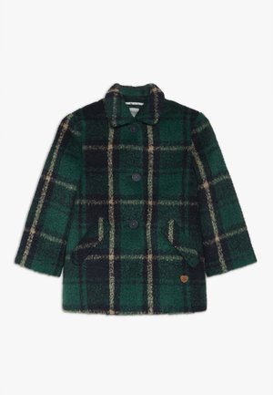 Abrigo de lana a cuadros verdes y negros con tres botones, dos bolsillos frontales con solapas y un pequeño emblema en forma de corazón en la parte inferior delantera.