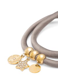 Collier en tissu beige avec des perles rondes dorées et trois pendentifs : un disque texturé, une étoile ornée de strass, et un charm circulaire lisse.