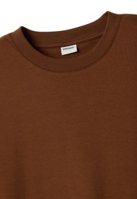 Camiseta de algodón marrón con cuello redondo y textura suave. Presenta un cuello acanalado y la etiqueta de la marca "STEFANEL" cosida en el interior.