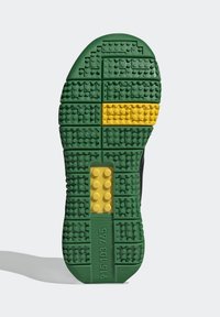 Podešev boty s zelenými a žlutými LEGO kostkami uspořádanými do mřížky, obsahujícími čísla a detaily loga LEGO.