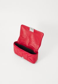 Clutch in pelle trapuntata rossa con chiusura in argento. L'interno è foderato in nero, con una texture liscia e una forma ben strutturata.
