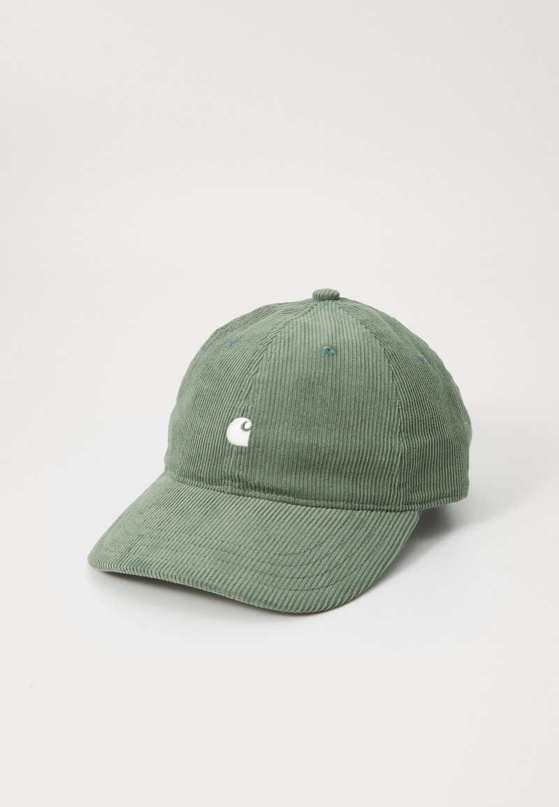 Vihreä corduroy-baseball-lippis, jossa on kaareva lippa, etupuolella valkoinen logo, tekstuuri kangasta ja kuusi ilmanvaihtoaukkoa.