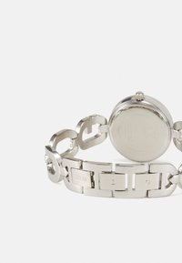 Orologio in acciaio inossidabile argentato con design a bracciale a maglie, dotato di cassa circolare e logo del marchio inciso sul cinturino.