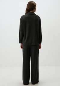 Grijs verticaal gestreept outfit met een losvallende lange mouw top en brede broek, gemaakt van gestructureerde stof. Eenvoudige kraagdetails.