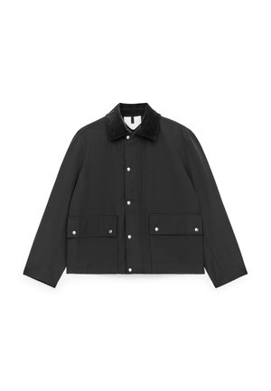 Sort vandtæt jakke med en manchet i fløjl, trykknapslukning, to forlommer og lange ærmer. Glat tekstur, moderne design.