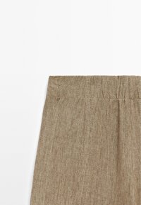 Světlé hnědé kalhoty s měkkou texturou, vybavené nařaseným elastickým pasem a jemnými sklady pro pohodlné nošení.