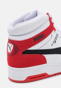 Basket haute Puma Slipstream blanche avec des accents en daim rouge, une bande noire et un col rembourré, mettant l'accent sur les détails arrière et latéraux.