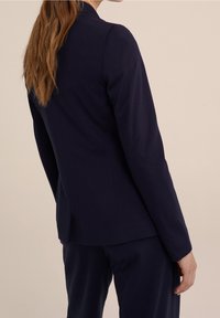 Marinblå figursydd blazer med en slät textur, strukturerade axlar och en enda ventil på baksidan, i kombination med matchande byxor.