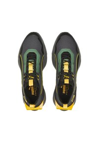 Ein Paar schwarze, grüne und gelbe Puma Sportschuhe mit Obermaterial aus Mesh und Schlaufen, von oben auf einem weißen Hintergrund betrachtet.