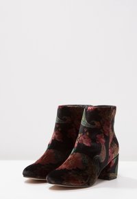 Zijden enkelboots in zwart met een kleurrijk bloemenpatroon, voorzien van een blokhak en puntige neus. Gladde textuur en elegant ontwerp.