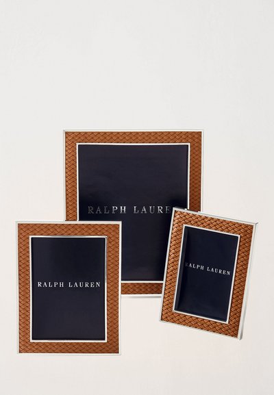 Trois cadres photo rectangulaires avec des accents en osier marron et des bords en argent, présentant un fond sombre avec le texte "RALPH LAUREN" en blanc.