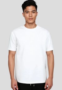 Hvid kortærmet t-shirt, rund hals, afslappet pasform, glat tekstur, med en sidelukning som designdetalje.