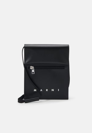 Sac à bandoulière en cuir noir avec une poche avant zippée, logo embossé et une bandoulière ajustable. Texture lisse avec une forme structurée.