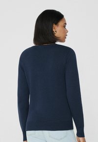 Marineblaues Strickpullover mit rundem Halsausschnitt und langen Ärmeln, mit geripptem Saum und Bündchen. Glatte Textur, figurbetonter Schnitt.