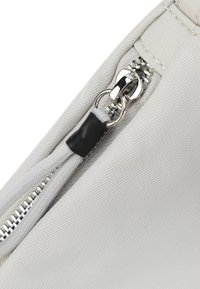 Custodia con zip in tessuto grigio chiaro, dotata di una zip in metallo, accento in gomma nera sulla zip e un dettaglio di superficie testurizzata.