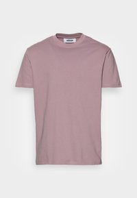 T-shirt à manches courtes rose clair en coton doux, avec un col rond et un design minimaliste. L'étiquette indique "minimum."
