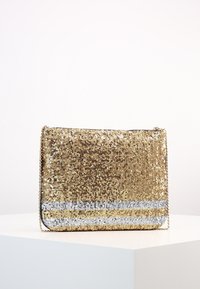 Kultainen paljeteilla koristeltu clutch-laukku suorakulmaisen muotoisena, hopeinen vaakasuora raita alaosassa ja ketjuhihna kantamista varten.