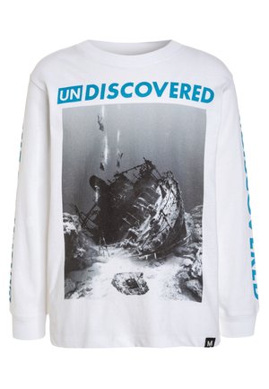 Camicia bianca a maniche lunghe con grafica di un relitto subacqueo e subacquei, testo in grassetto blu "UN DISCOVERED" sopra l'immagine.