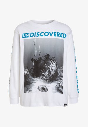Camiseta blanca de manga larga con gráfico de naufragio submarino y buzos, texto azul intenso "UN DISCOVERED" encima de la imagen.