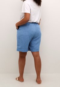 Pantaloncini azzurri realizzati in tessuto strutturato, dotati di vita elasticizzata e tasche laterali, orlati appena sopra il ginocchio.