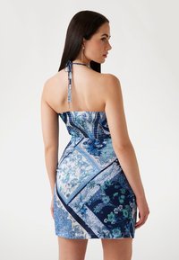 Rochie mini fără bretele în nuanțe de albastru, cu modele florale și geometrice, bust cu elastic și legătură la gât. Textură de țesătură netedă.