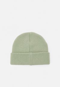 Gorro de malha em verde claro, com uma dobra na bainha e acabamento texturizado. Parte superior circular com padrão canelado em todo o gorro.