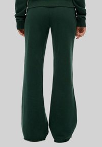 Pantalons de survêtement évasés vert foncé avec une texture douce, dotés d'une taille haute et de jambes larges, conçus pour le confort et un style décontracté.