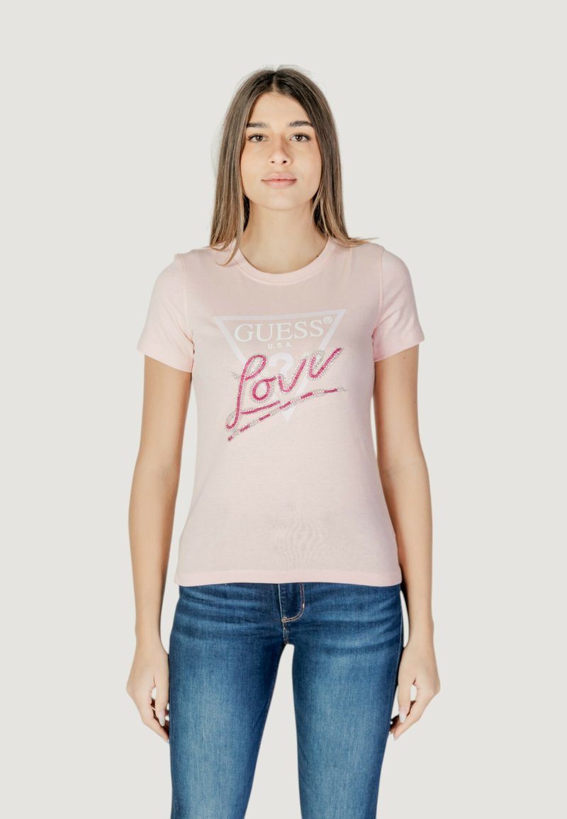 Camiseta de algodón rosa claro con mangas cortas, que presenta un logo triangular de "GUESS" y el texto brillante "Love" en color rosa. Diseño ajustado, textura suave.
