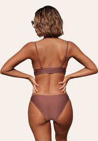 Bikini marrone a coste con spalline sottili regolabili, slip a taglio alto e una texture liscia, che mette in mostra un design aderente e dettagli minimi.
