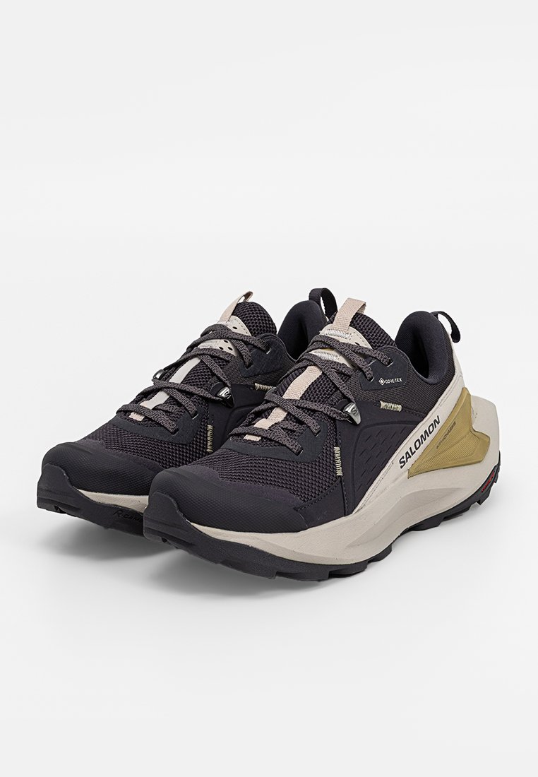 Schwarze und beiges Außenschuhe mit strukturiertem Mesh und synthetischen Überzügen, die eine gepolsterte Sohle und ein hervorgehobenes Logo an der Seite aufweisen.