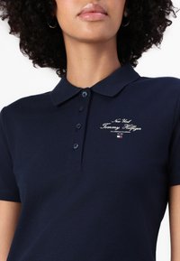 Marine polo skjorte i bomullsblanding, med krage, tre knapper og broderi med "Tommy Hilfiger" og logo detaljer på brystet.