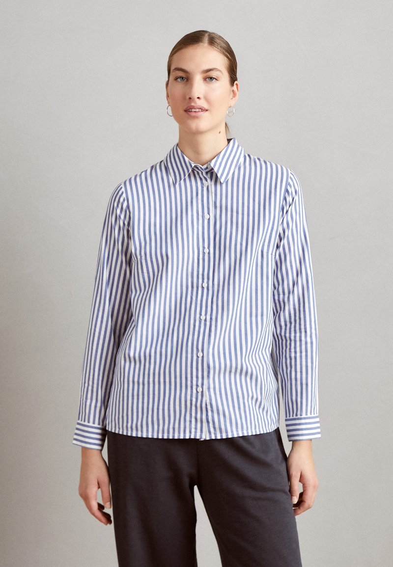 Camicia a righe blu e bianca in cotone. Presenta un colletto a punta e maniche lunghe con polsini abbottonati. Retro semplice e senza tasche.