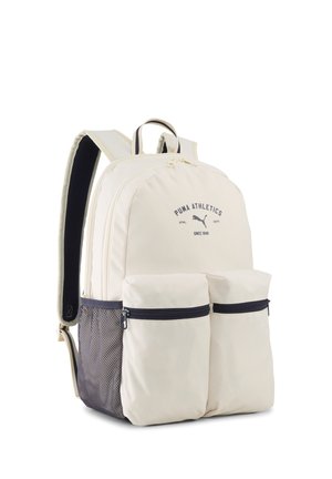 Kremowy plecak Puma z dwiema przednimi kieszeniami na zamek, siatkową kieszenią boczną, wyściełanymi szelkami oraz logo Puma Athletics na głównym przedziale.