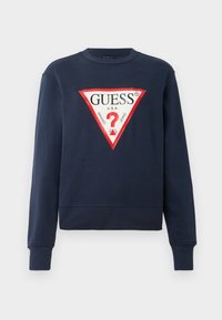 Marineblaue Langarm-Sweatshirt mit einem großen weißen und roten dreieckigen Guess-Logo mit einem Fragezeichen auf der Brust.