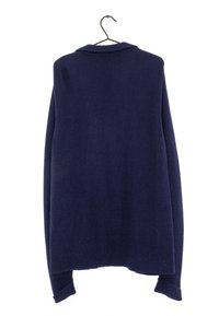 Mörkblå tröja gjord av ribbad stickad tyg, med krage och långa ärmar, hängande från en svart krok mot en vit bakgrund.