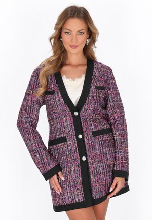 Violetti ja vaaleanpunainen tweed-takki mustilla yksityiskohdilla. Varustettu kolmella napilla, kahdella taskulla ja kohokuvioidulla kankaalla, jossa on ruutukuosi.