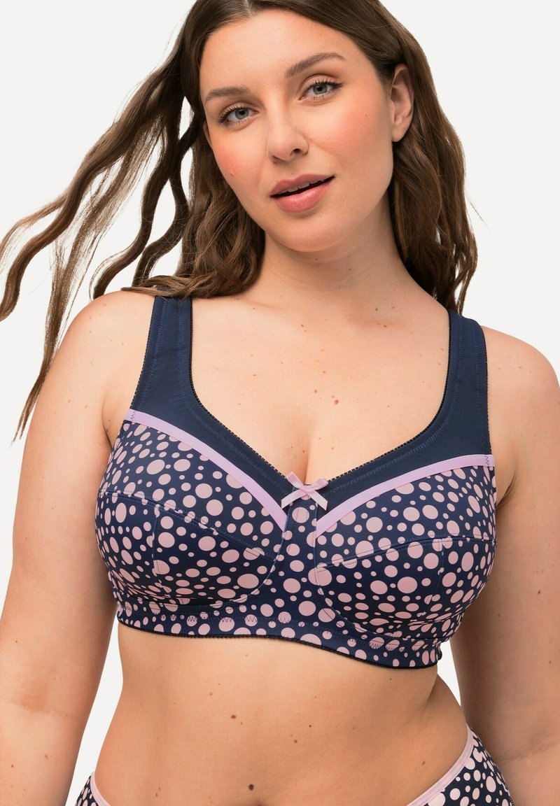Marineblauwe beha met roze stippen, brede bandjes, zachte textuur, een kanten rand en een klein strikje in het midden vooraan.