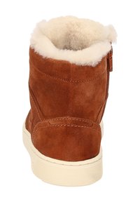 Braune Wildleder-Stiefelette mit weißem Fellfutter, glatter Oberfläche und creamfarbener Gummisohle. Besitzt einen seitlichen Reißverschluss für einfaches An- und Ausziehen.