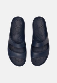 Námořnické modré skluzové sandály vyrobené z texturovaného plastu s třemi širokými popruhy a tvarovanou stélkou se tečkovaným vzorem pro lepší přilnavost.