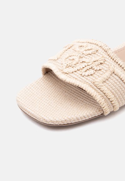 Μπεζ υφαντό σανδάλι-σλάιντ με φαρδιά κεντημένη λουρίδα που φέρει λουλουδένια σχέδια και τετράγωνο σχέδιο στη μύτη.