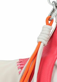 Détail d'un sac en cuir blanc et rose avec des accents de corde orange, une couture complexe et un clip en métal pour l'attache.
