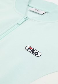 Veste zippée menthe claire avec col côtelé et patch logo FILA sur la poitrine.