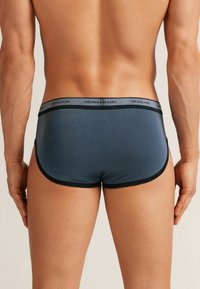 Męska bielizna w ciemnoniebieskim kolorze z mieszanki bawełny, z czarnym elastycznym pasem z logo. Gładka tekstura i dopasowany krój z zaokrąglonymi krawędziami.