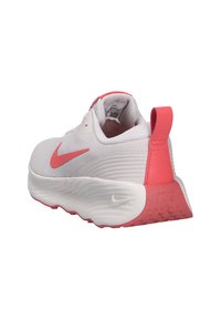 Zapatillas Nike con empeine de malla blanca, detalles en rosa, diseño de suela curvada y una lengüeta en el talón de color rosa con detalle de marca.