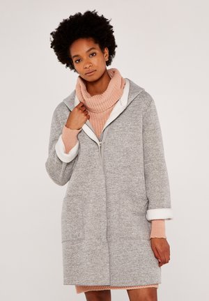 Gray, zip-up coat featuring a hood and white, fleece-lined cuffs; includes two front pockets. Worn over a pink, knitted turtleneck sweater.