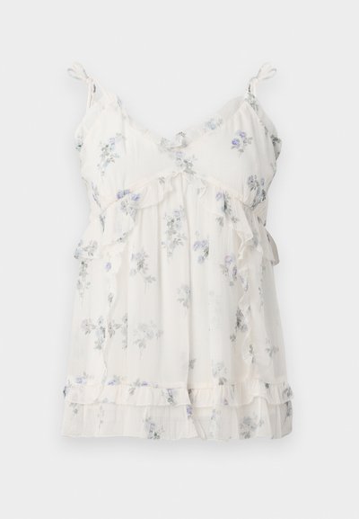 Top de tip tank floral, dintr-un material alb ușor și semi-transparent. Prezintă accente volănașe și bretele ajustabile, cu modele florale în nuanțe de mov.