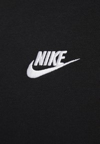 Svart tyg med en slät textur har en vit broderad Nike-logotyp som visar upp varumärkets ikoniska swoosh-design.